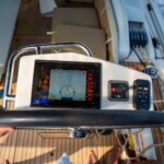 View from above of a man steering a sailing yacht using navigation display and control panel near Croatia. Precision, control and modern sailing lifestyle at sea. High quality photo