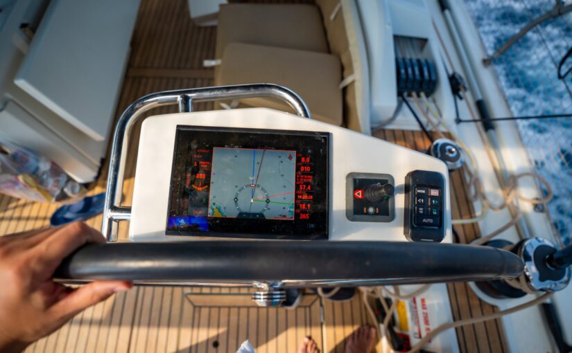 View from above of a man steering a sailing yacht using navigation display and control panel near Croatia. Precision, control and modern sailing lifestyle at sea. High quality photo